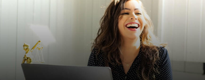A woman smiling while working on a computer.