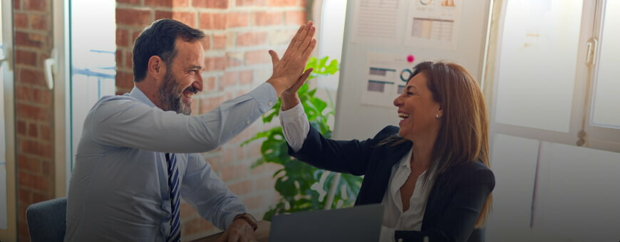 Two business professionals high-fiving in an office.