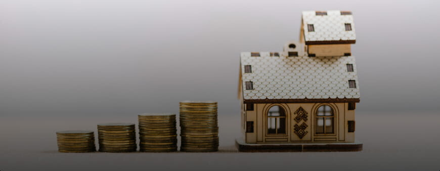 A small figurine of a house with stacks of coins next to it.