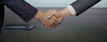 Two professionals in suits shaking hands.