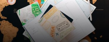 A visa, planner, and street map sitting atop a world map.